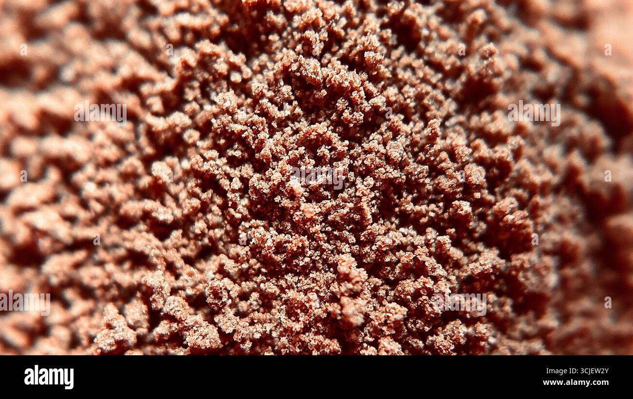 Vista ravvicinata della polvere di cioccolato marrone ricco, che mostra la sua consistenza fine, i grani morbidi e la superficie ricca di cacao, spesso utilizzata nei dessert, nella cottura, nelle bevande, Foto Stock