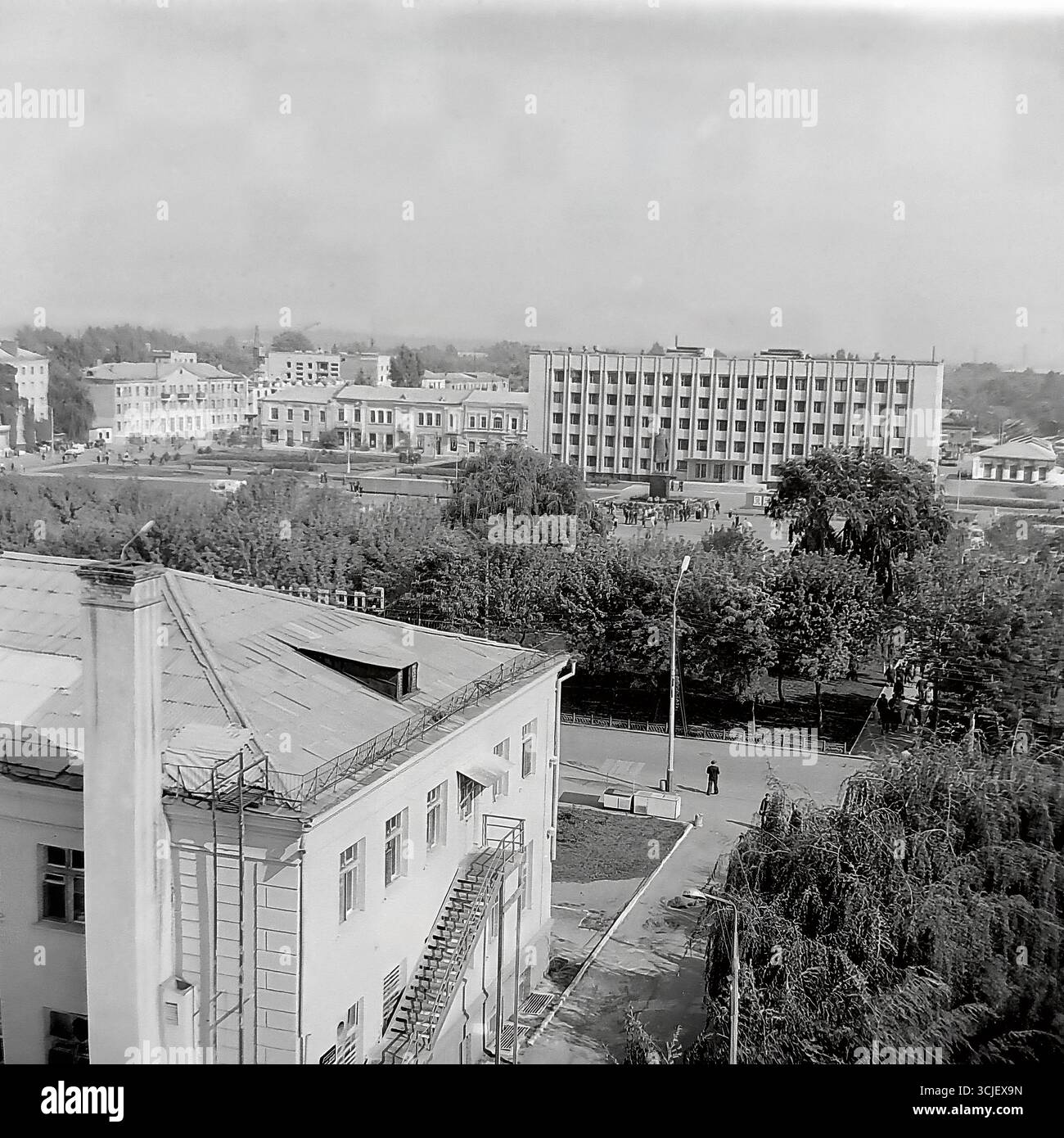Una vista panoramica della piazza centrale della Rivoluzione d'ottobre (ora piazza Soborna) nella città di Slavyansk durante la seconda metà degli anni '1970, che mostra il cuore di una città sovietica nell'era della stagnazione: L'edificio monumentale del comitato esecutivo della città, il monumento Lenin e un giardino pubblico ben tenuto, catturato da un punto alto in un tranquillo giorno feriale, che serve da preziosa testimonianza della vita pacifica Donbas Foto Stock