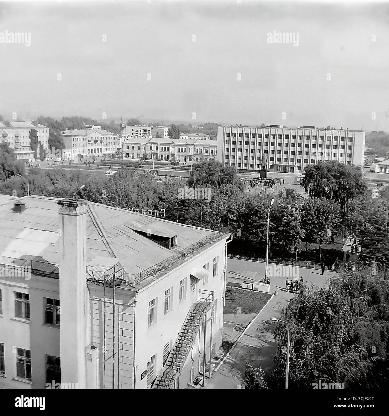 Una vista panoramica della piazza centrale della Rivoluzione d'ottobre (ora piazza Soborna) nella città di Slavyansk durante la seconda metà degli anni '1970, che mostra il cuore di una città sovietica nell'era della stagnazione: L'edificio monumentale del comitato esecutivo della città, il monumento Lenin e un giardino pubblico ben tenuto, catturato da un punto alto in un tranquillo giorno feriale, che serve da preziosa testimonianza della vita pacifica Donbas Foto Stock
