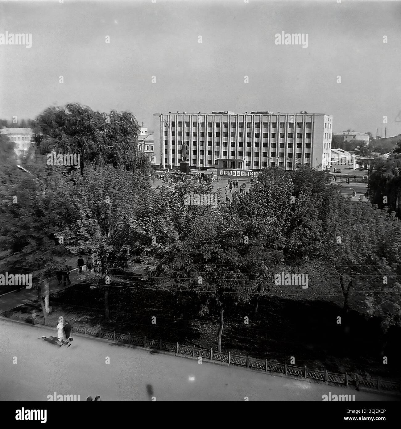 Una vista panoramica della piazza centrale della Rivoluzione d'ottobre (ora piazza Soborna) nella città di Slavyansk durante la seconda metà degli anni '1970, che mostra il cuore di una città sovietica nell'era della stagnazione: L'edificio monumentale del comitato esecutivo della città, il monumento Lenin e un giardino pubblico ben tenuto, catturato da un punto alto in un tranquillo giorno feriale, che serve da preziosa testimonianza della vita pacifica Donbas Foto Stock