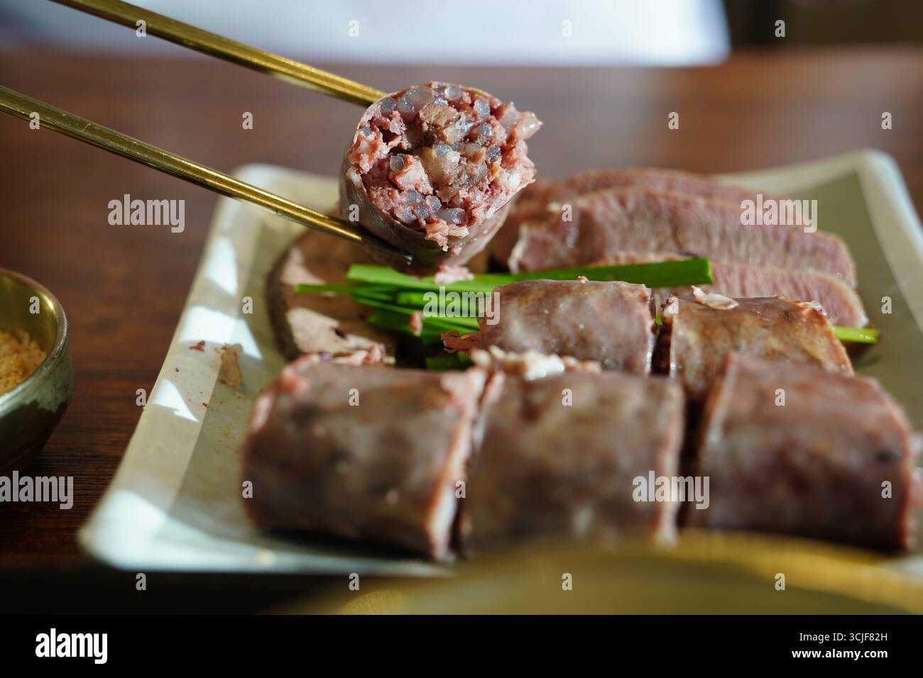 Salsiccia coreana (Sundae) a fette con cipolle verdi sul piatto Foto Stock