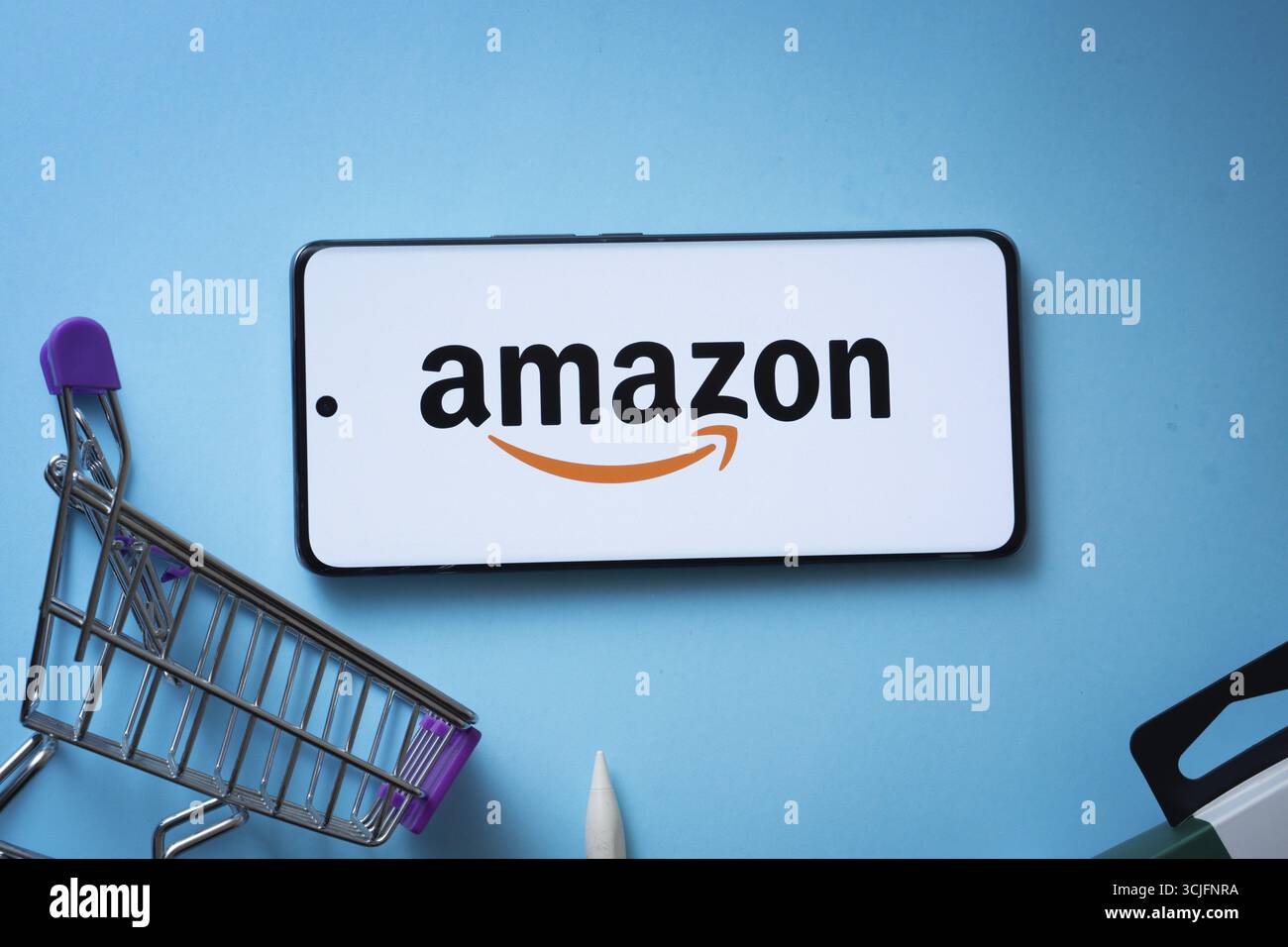 Dacca, Bangladesh - 3 luglio 2025: Smartphone con logo Amazon e carrello su sfondo blu Foto Stock