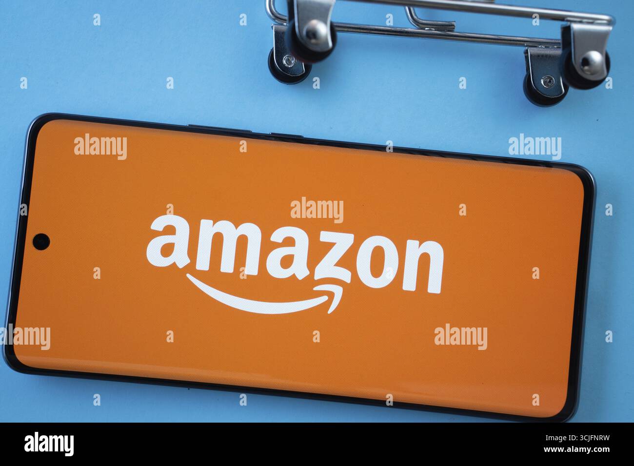 Dhaka, Bangladesh - 3 luglio 2025: Schermata dello smartphone con il logo Amazon e le ruote del carrello su sfondo blu Foto Stock
