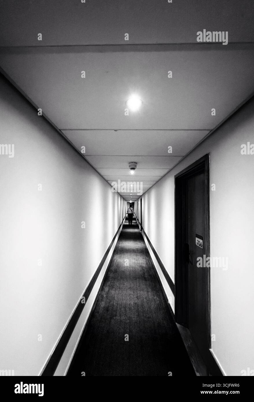 Figura nel corridoio dell'hotel con piscine di luce e pareti semplici Foto Stock