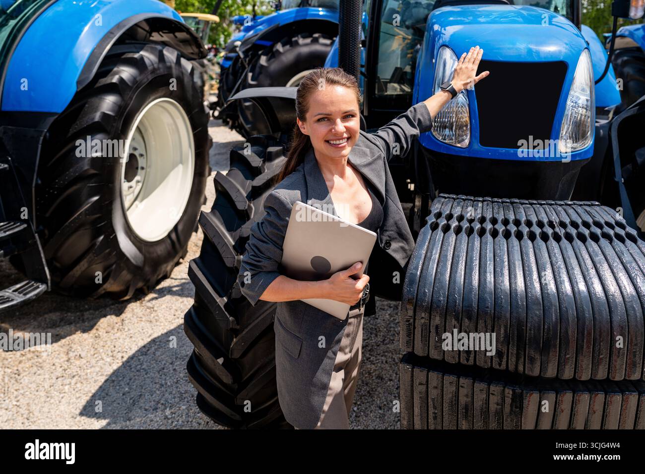 Concessionaria di attrezzature agricole. Donna responsabile vendite che mostra ai clienti nuovi trattori. Foto Stock