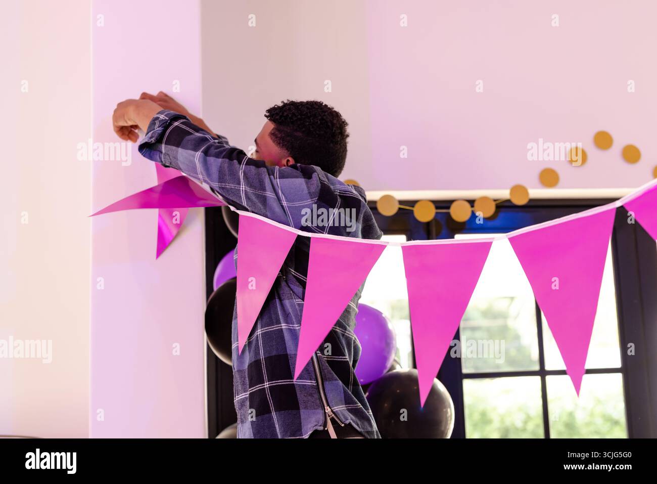 Uomo afroamericano che decora la sala con grappolo rosa per l'evento celebrativo Foto Stock