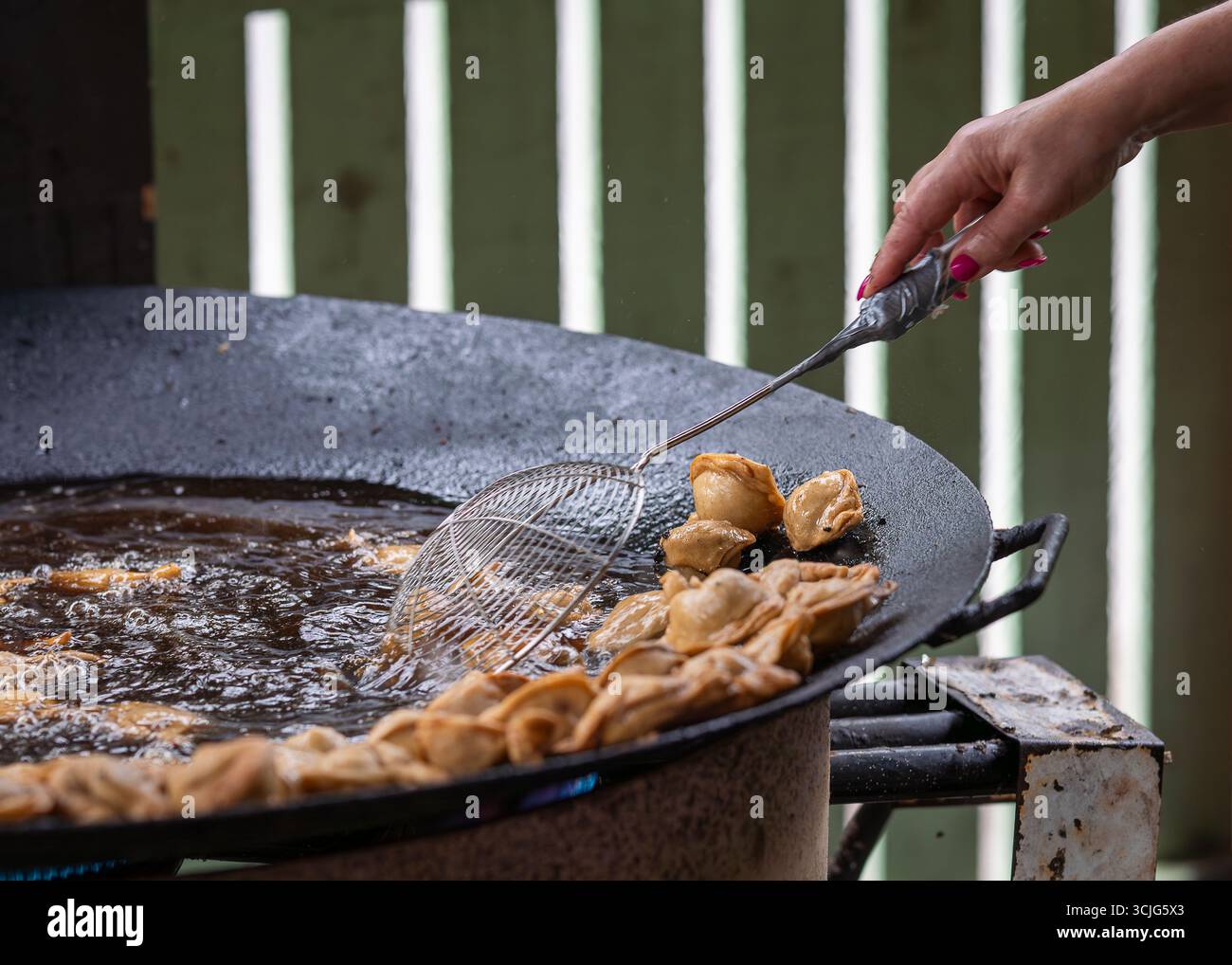 Pelmeni (gnocchi) friggere su una padella alla griglia durante il festival del cibo urbano. Lo chef prepara deliziosi pelmeni su una grigliata calda. Foto Stock