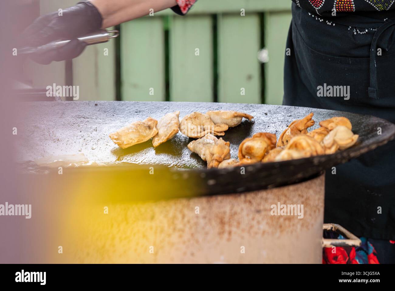 Pelmeni (gnocchi) friggere su una padella alla griglia durante il festival del cibo urbano. Lo chef prepara deliziosi pelmeni su una grigliata calda. Foto Stock