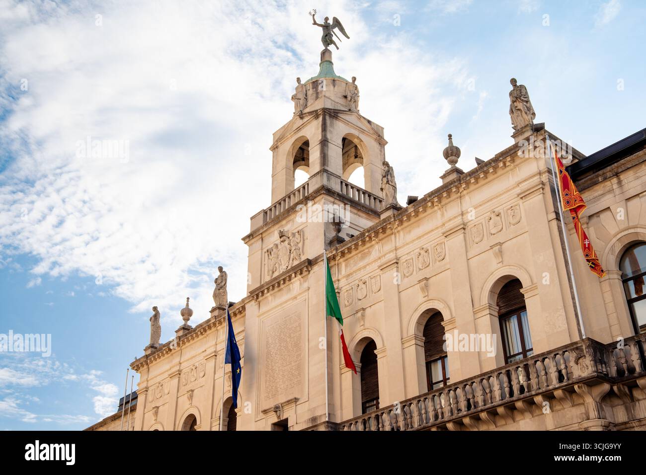 Facciata ornata di Palazzo Moroni, il municipio di Padova, in Italia, contro il cielo azzurro d'estate, con bandiere italiane ed europee Foto Stock