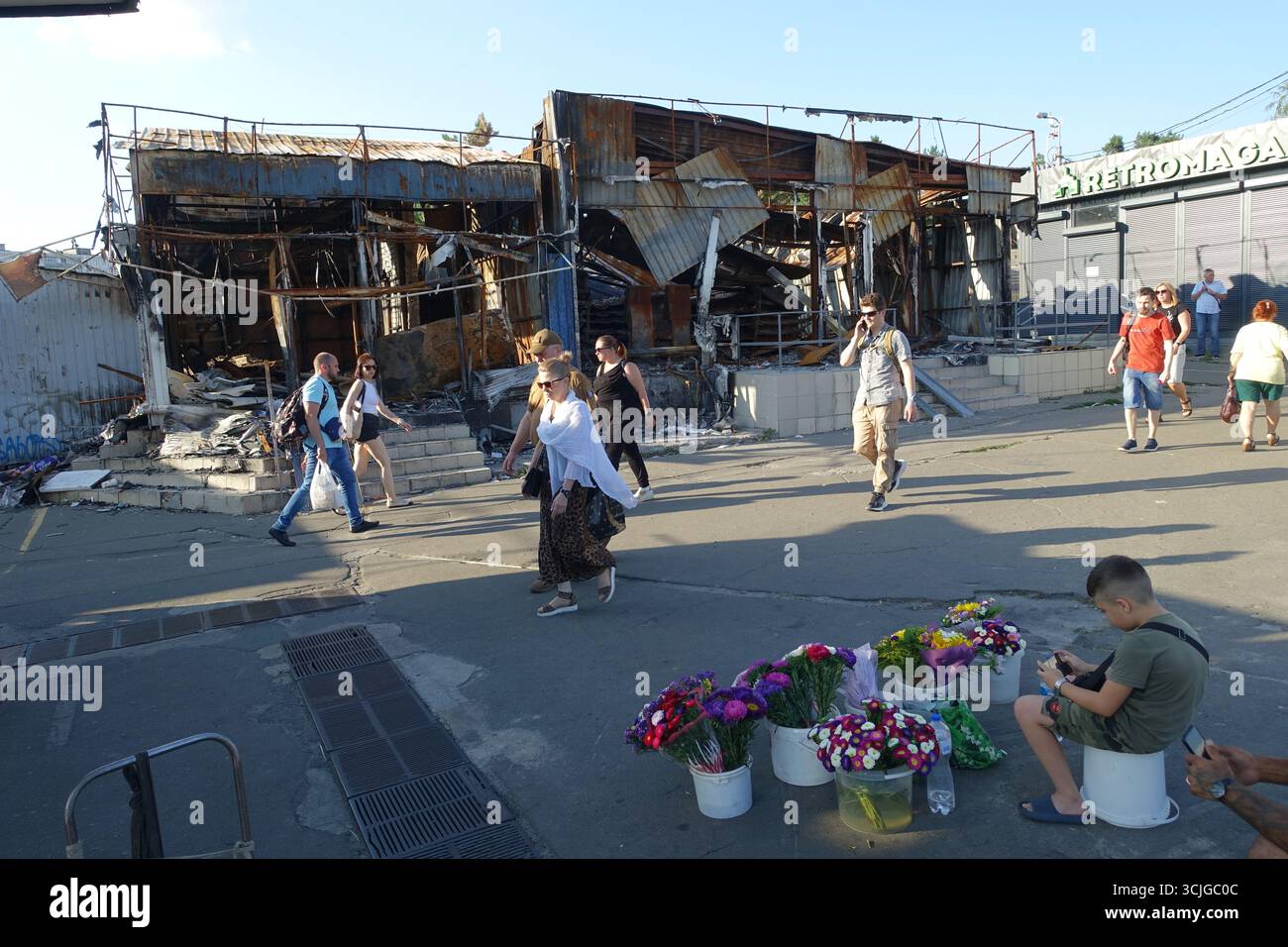 I civili passano davanti a un negozio distrutto da un bombardamento durante la notte in una zona residenziale di ​​kyiv Foto Stock