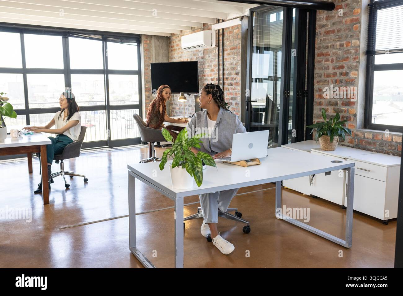 Colleghi in un ufficio moderno che collaborano e discutono idee con i notebook Foto Stock