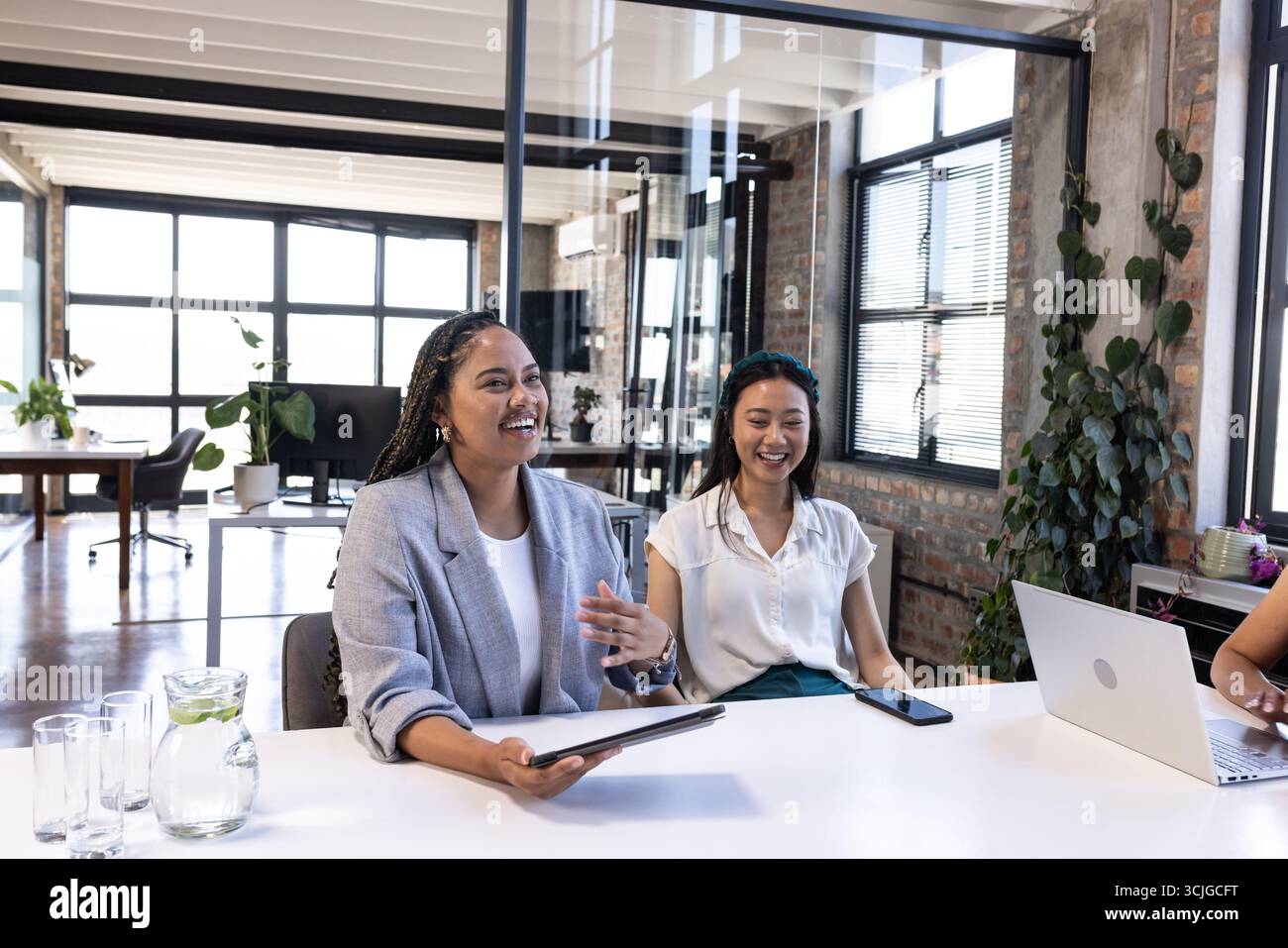 Colleghi in un ufficio moderno che celebrano il successo con risate e lavoro di squadra Foto Stock
