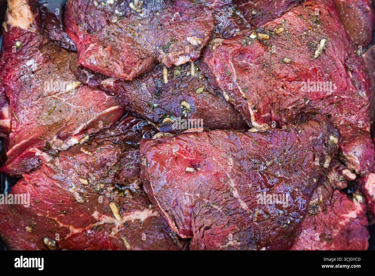 Pezzetti di carne fresca e succosa in spezie, primo piano. Bistecche crude di manzo, vista dall'alto. Foto Stock