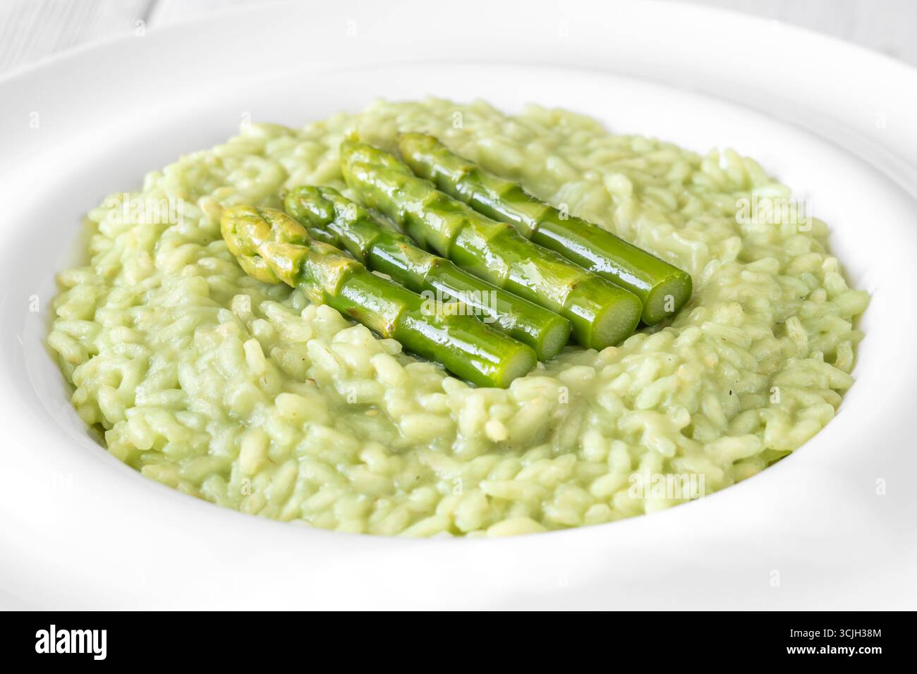 Risotto cremoso con punte di asparagi verdi, guarnito e presentato splendidamente Foto Stock