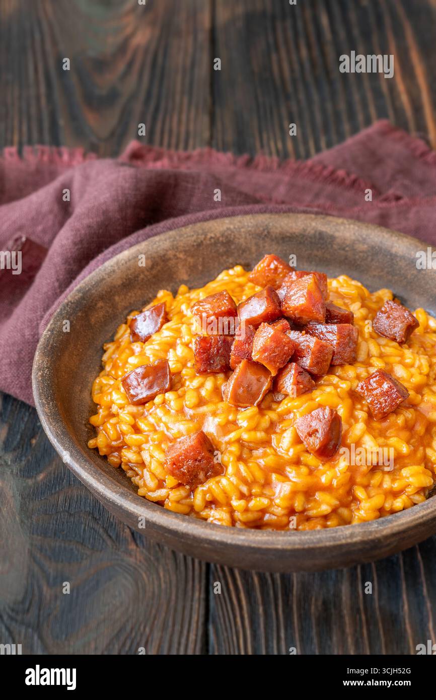 Risotto sostanzioso con chorizo, pomodori maturi ed erbe aromatiche servito in un rustico recipiente in ceramica Foto Stock