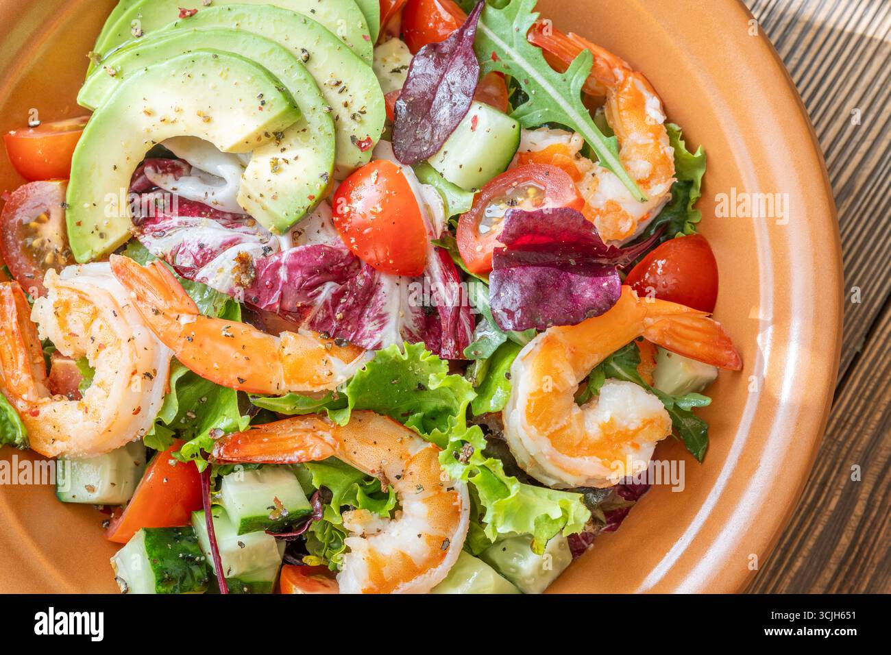 Vivace insalata di gamberi avocado verdure fresche condimento agrumi tavolo in legno rustico Foto Stock