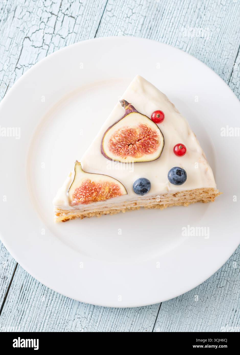 Torta al formaggio spalmabile con spicchi di fichi ribes mirtilli servita con piatto bianco Foto Stock