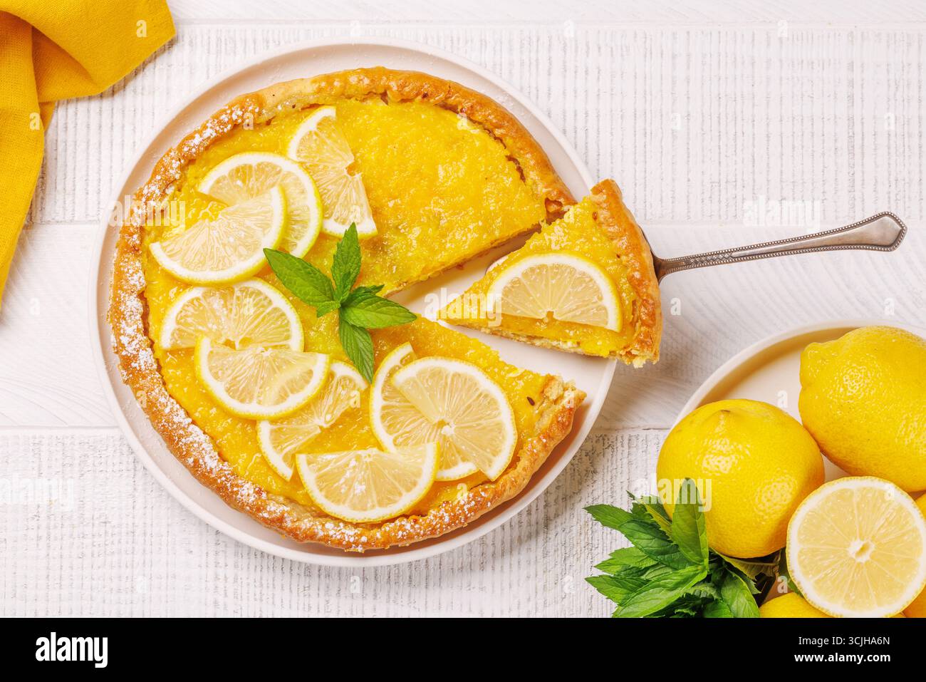 Deliziosa crostata al limone con crosta dorata e ripieno liscio e lucido al limone, leggermente guarnita Foto Stock