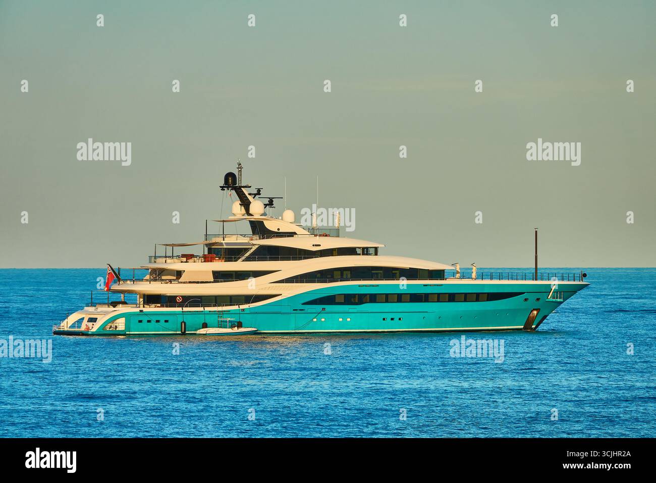 Lussuoso Superyacht Turchese, andate ad Anchor su un oceano tranquillo sotto il cielo limpido in un giorno luminoso Foto Stock