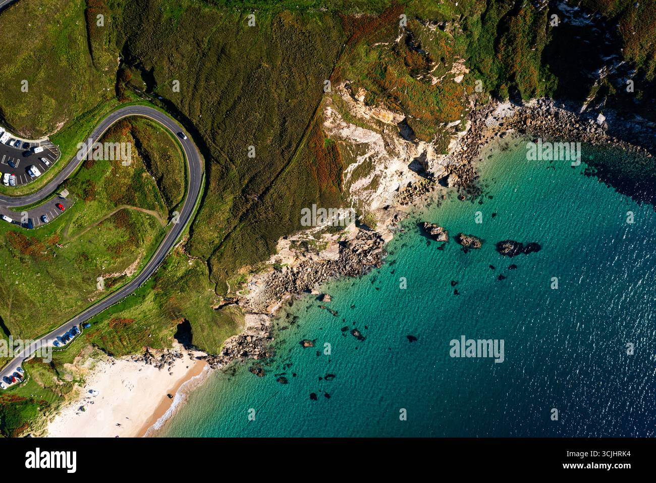 Vista aerea dall'alto verso il basso della strada tortuosa con un'auto e un parcheggio a Keem Beach sull'isola di Achill in Irlanda Foto Stock