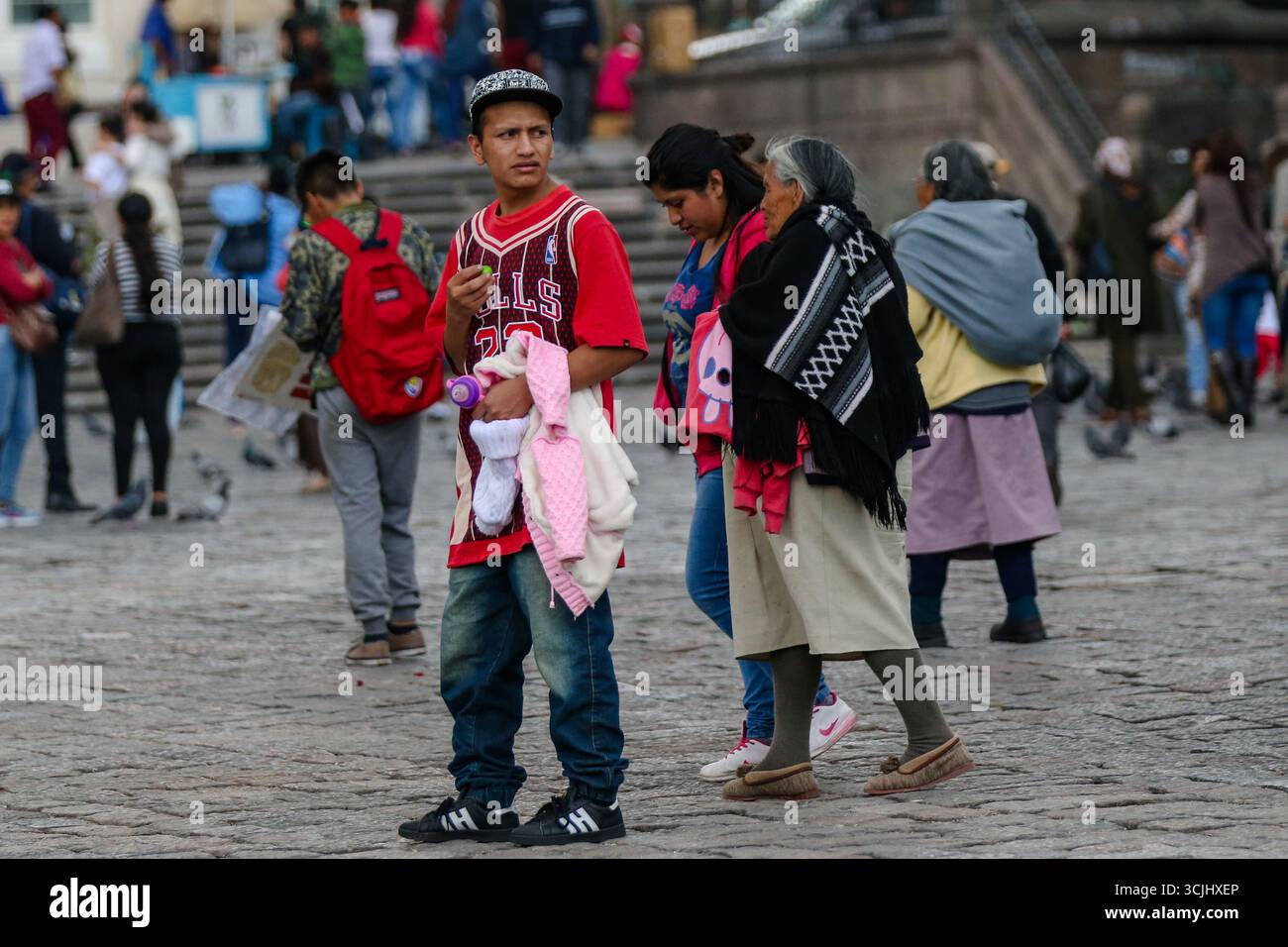 Quito, Ecuador – 23 marzo 2018: Le famiglie indigene camminano attraverso la storica Old Town plaza indossando i tradizionali scialli andini e gonne, Foto Stock
