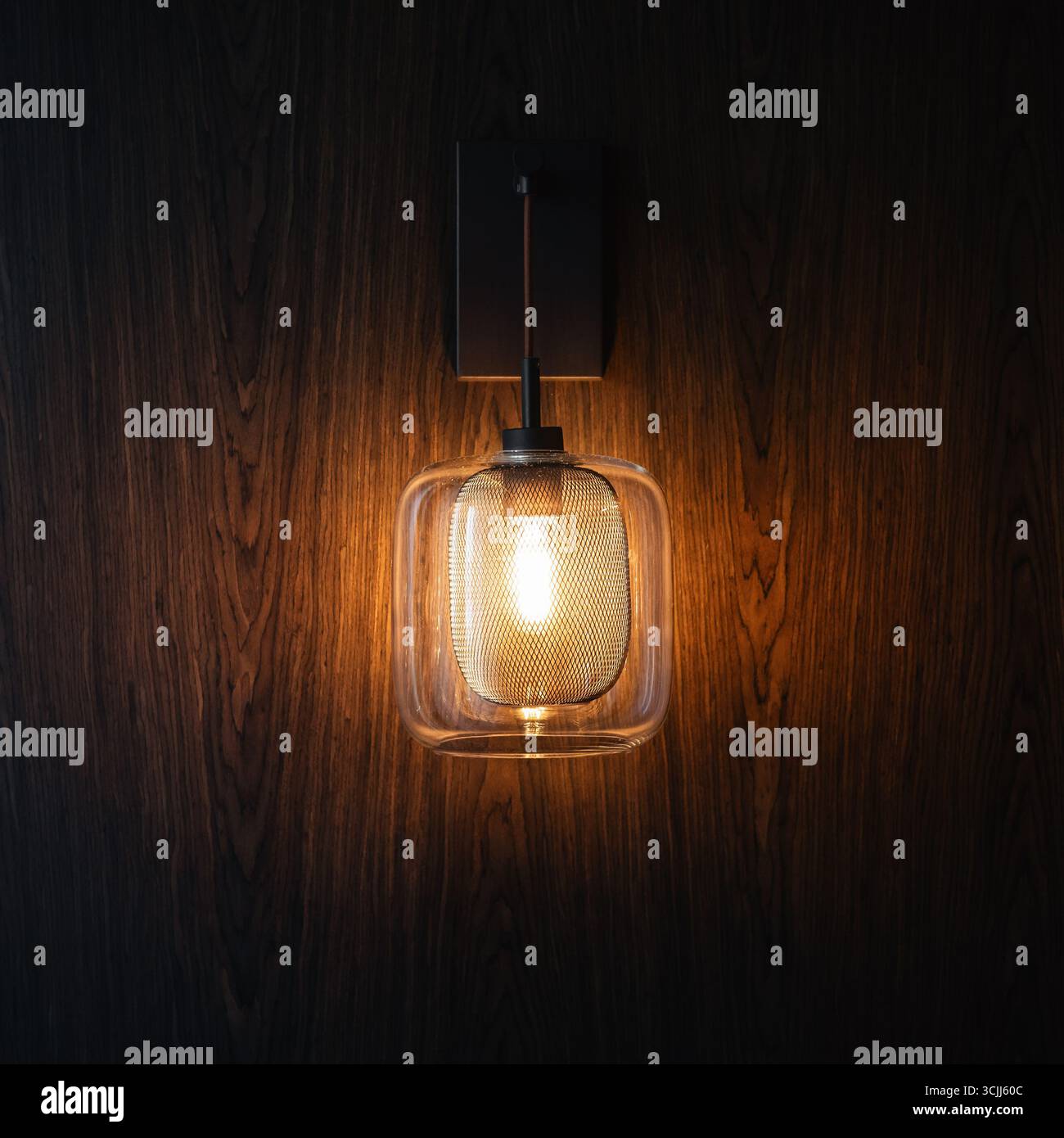 Lampadina su parete in legno. Lampadina stile Edison che emette una luce calda su sfondo marrone in legno. Foto Stock