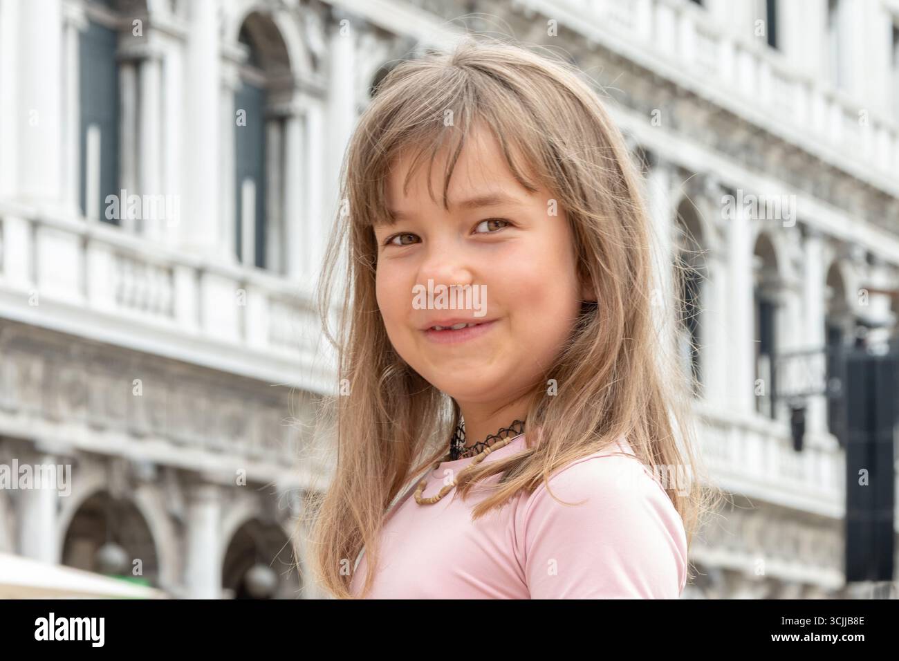 Una ragazza sorride di fronte a un vecchio edificio a Venezia Foto Stock