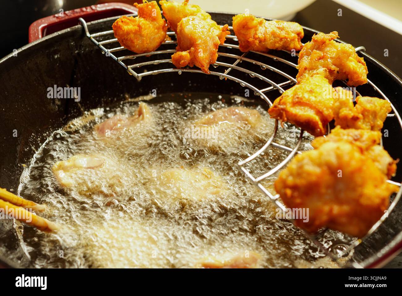 TORI NO KARAAGE (pollo fritto) - Una donna che frigge il pollo ricoperto di pastella in olio caldo Foto Stock