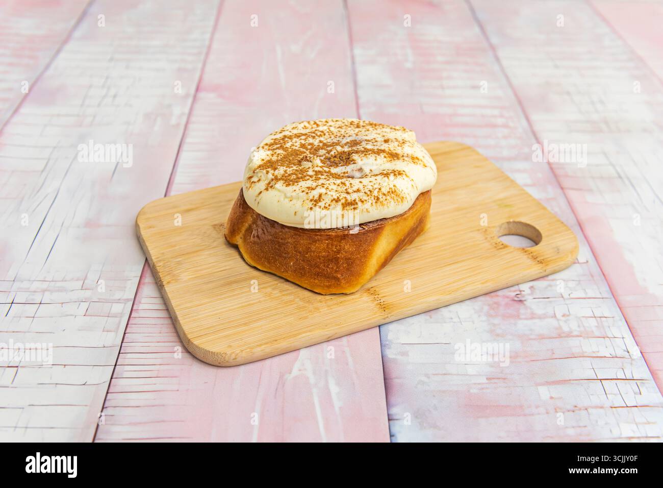 Involtini alla cannella appena sfornati con glassa al cioccolato bianco e cocco grattugiato. Modanatura Foto Stock