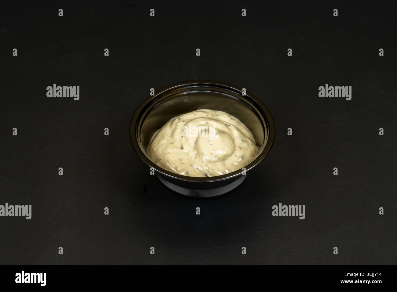 Mini contenitori in ceramica con maionese all'aglio, decorati con prezzemolo appena tritato a contrasto con il bianco della salsa Foto Stock