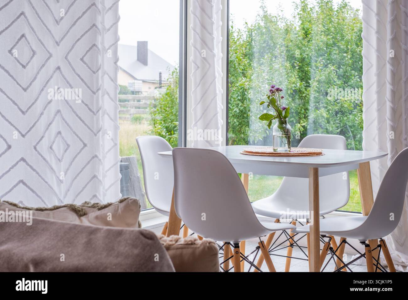 La zona pranzo di ispirazione scandinava presenta un design minimalista con arredi funzionali, un ambiente luminoso e arioso e tessuti accoglienti, perfetti per il moderno Foto Stock
