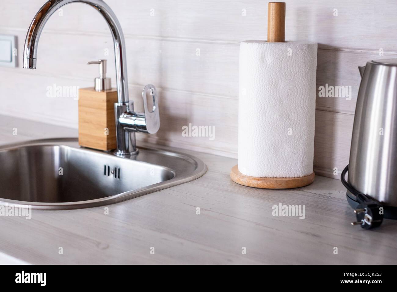 Gli interni della cucina scandinava presentano un design minimalista con un lavandino in acciaio inossidabile, accenti in legno e un bollitore moderno, sottolineando una luminosa a Foto Stock