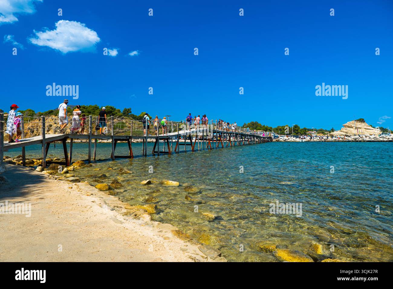Ponte in legno che conduce all'isola di Cameo, Zante, in Grecia, con acque turchesi cristalline sottostanti e turisti che camminano attraverso il popolare luogo di viaggio di instagram Foto Stock Ponte in legno che conduce all'isola di Cameo, Zante, in Grecia, con acque turchesi cristalline sottostanti e turisti che camminano attraverso il popolare luogo di viaggio di instagram Foto Stock