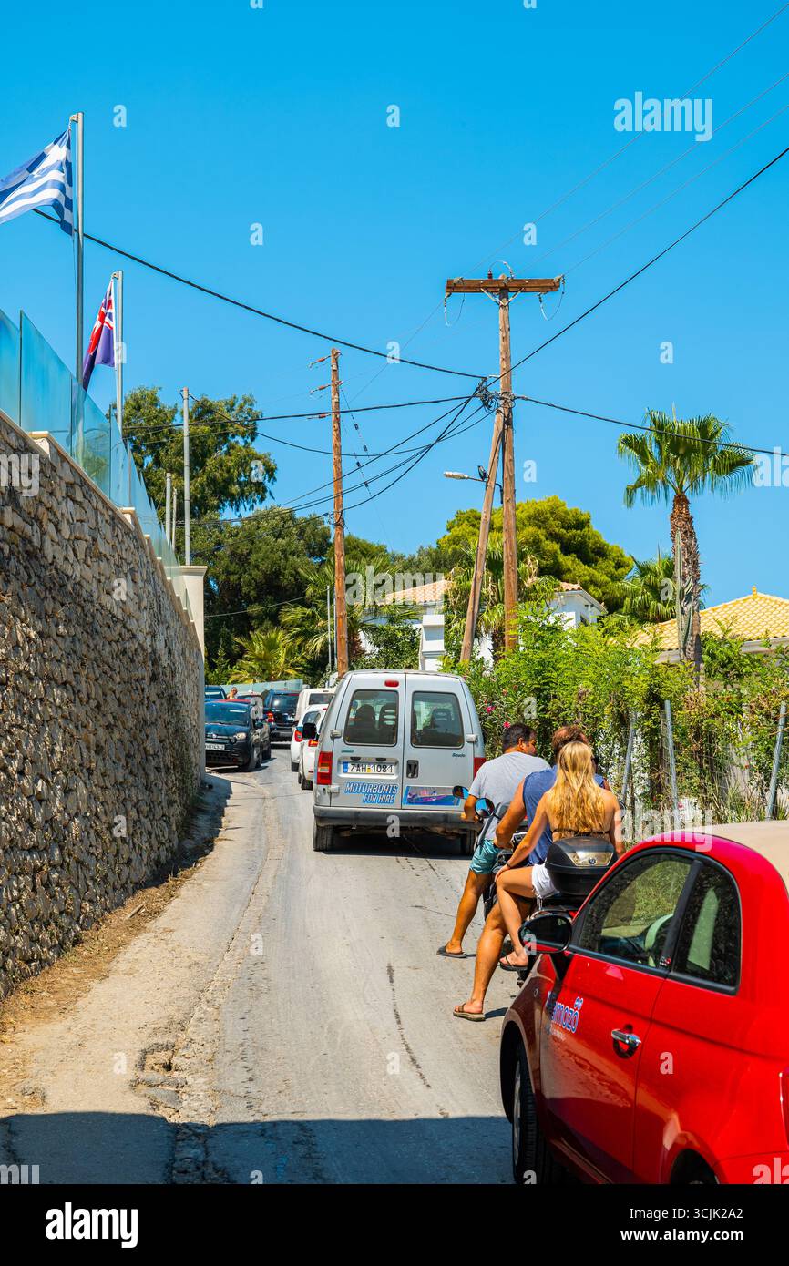 Strada stretta nell'isola di Zante in Grecia, con auto che guidano nel traffico tra muri di pietra alberi verdi Foto Stock Strada stretta nell'isola di Zante in Grecia, con auto che guidano nel traffico tra muri di pietra alberi verdi Foto Stock