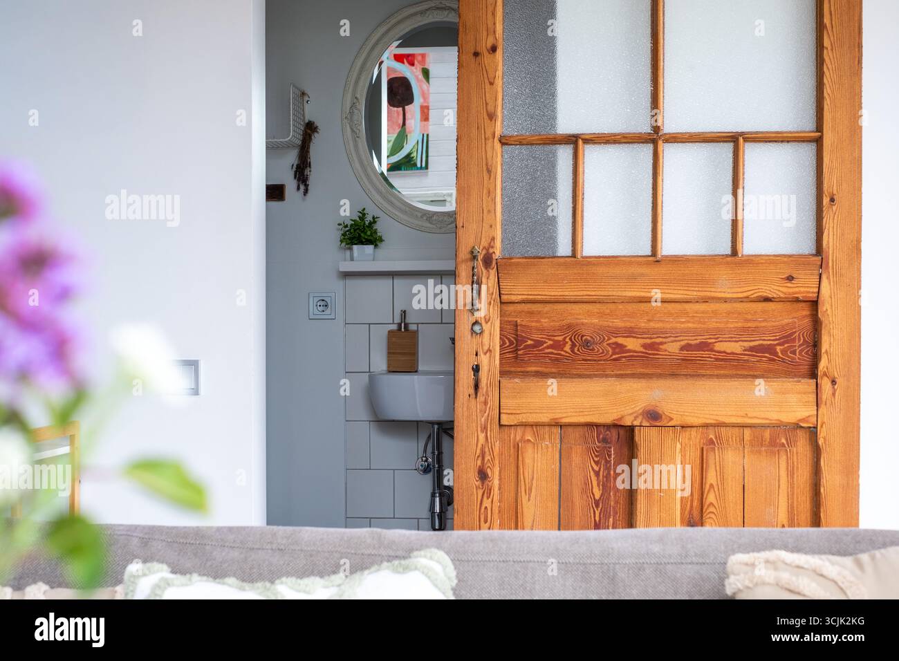 Luminosi interni scandinavi con una porta rustica in legno che conduce ad un'area funzionale, il decor minimalista accentua l'atmosfera intima e ariosa della S. Foto Stock