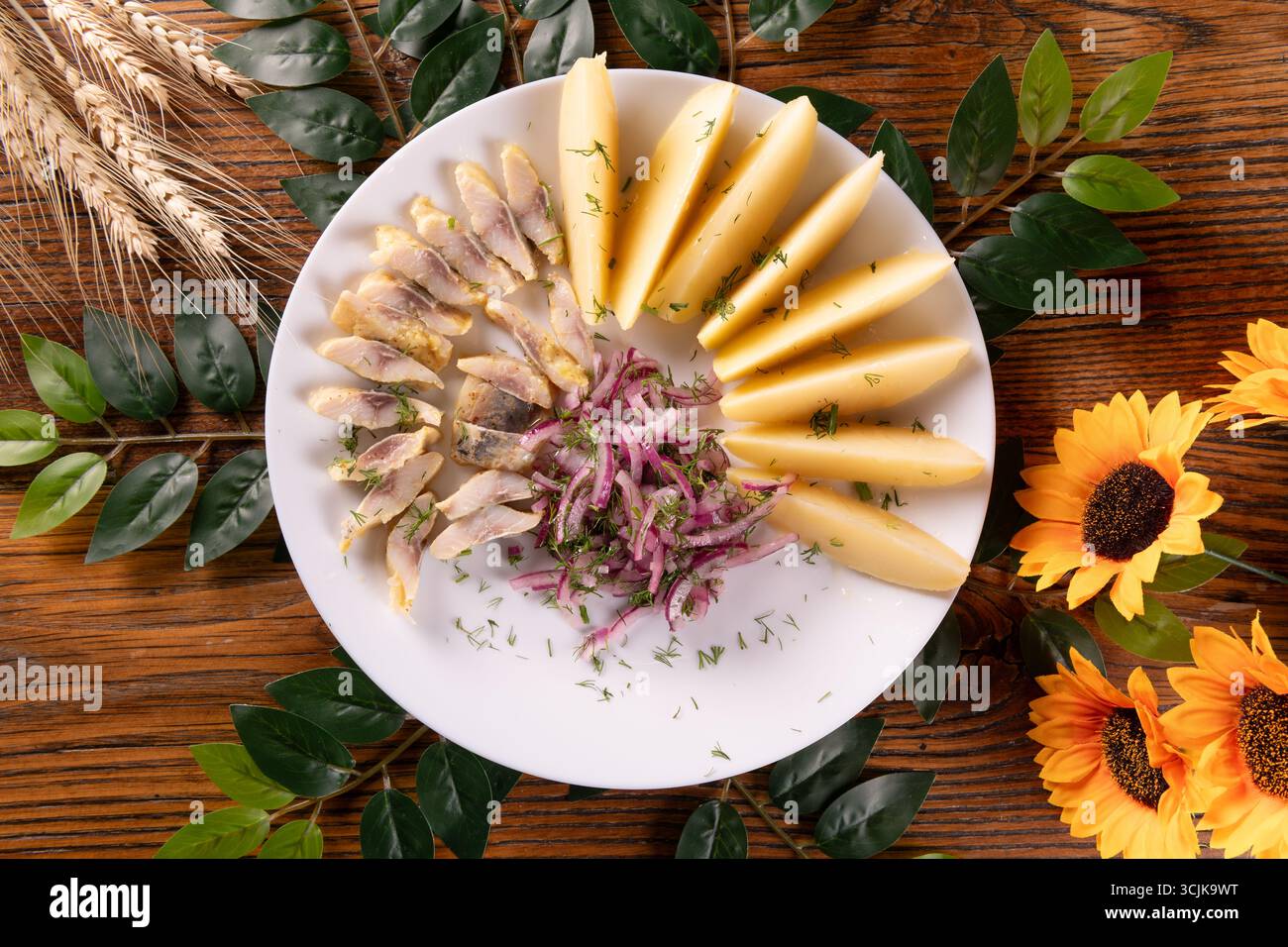Una foto che mostra un piatto tradizionale ucraino di pesce aringa servito con patate, mostrando una presentazione abbondante e saporita su un piatto rustico. Foto Stock