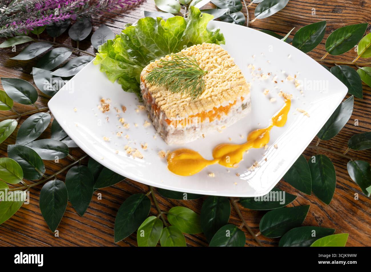 Una foto con Mimosa, una tradizionale insalata Ucraina a strati con pesce e maionese, presentata con colori vivaci e una texture delicata. Foto Stock