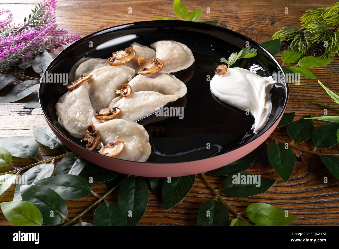 Una foto che ritrae Vareniki, un tradizionale gnocco ucraino, presentato con un ripieno saporito e servito con un cucchiaio di panna acida ed erbe aromatiche Foto Stock