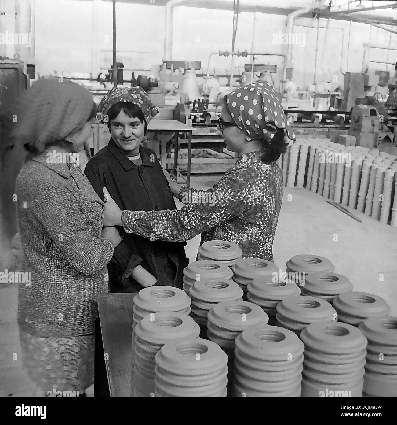 Tre lavoratrici in un laboratorio dell'impianto isolante ad alta tensione di Slavyansk (ZVI) durante una vivace conversazione durante una pausa, 1976. Questo sincero scatto d'archivio dell'era della stagnazione, che cattura l'amicizia e la moda degli anni '70 in un ambiente di lavoro, è un simbolo delle relazioni umane in un collettivo operaio e della vita serena di un Donbas pacifico Foto Stock