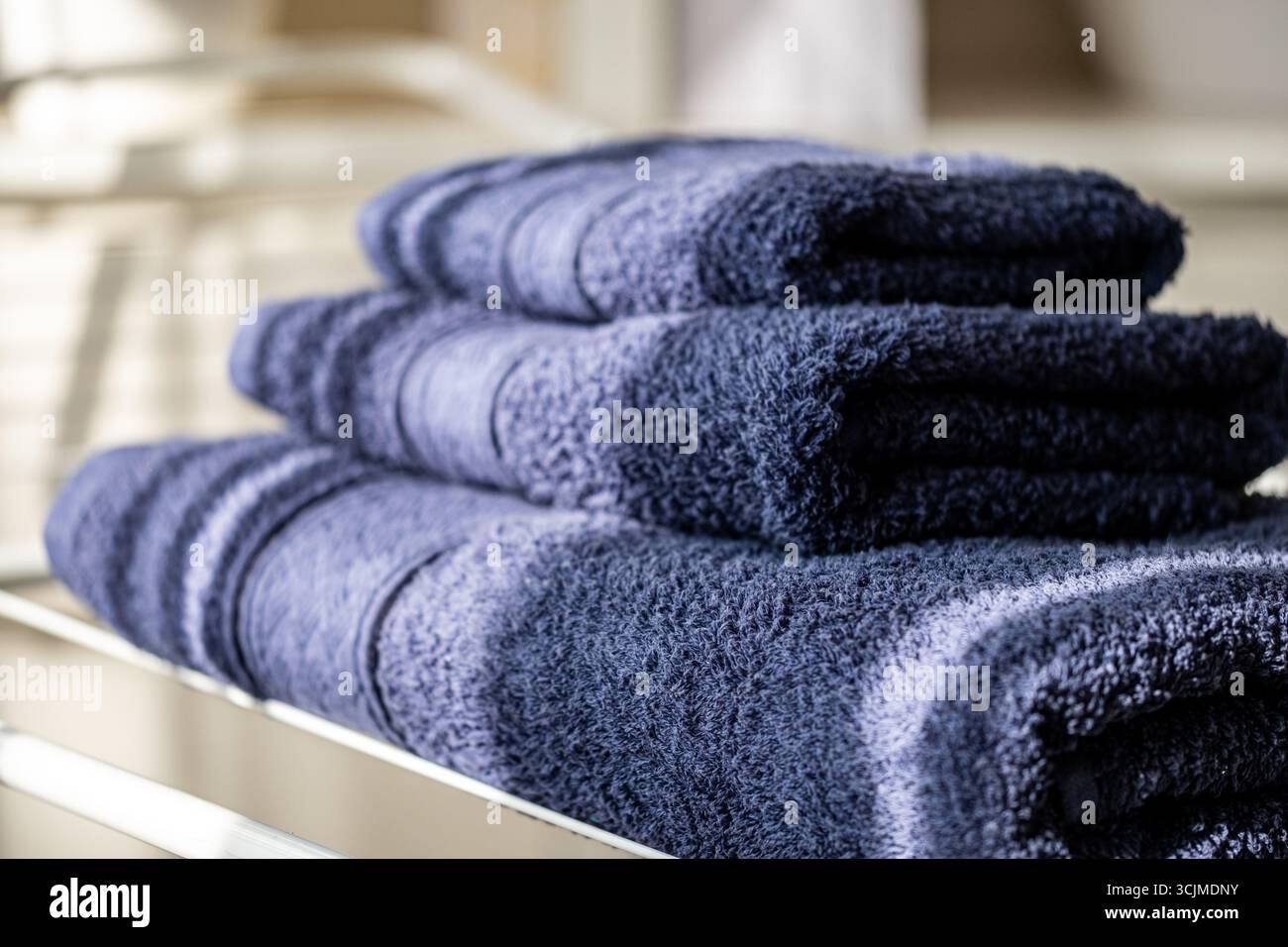 Gli asciugamani morbidi e ben piegati sono disposti in modo organizzato, migliorando l'accogliente ambiente del bagno con tessuti freschi e un aspetto pratico e ordinato Foto Stock