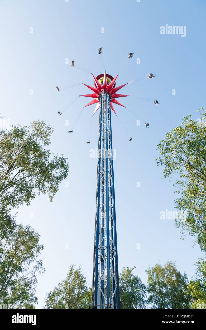 Filmato di un'altalena che gira su un cielo blu con nuvole e il movimento di un parco divertimenti in una giornata di sole Foto Stock
