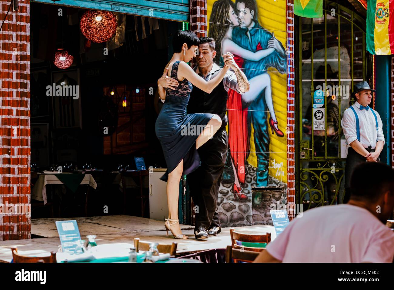 Buenos Aires, Argentina - 22 dicembre 2022: I ballerini di Tango si esibiscono su un palco marciapiede nel quartiere Caminito di la Boca, con pitture murali colorate Foto Stock