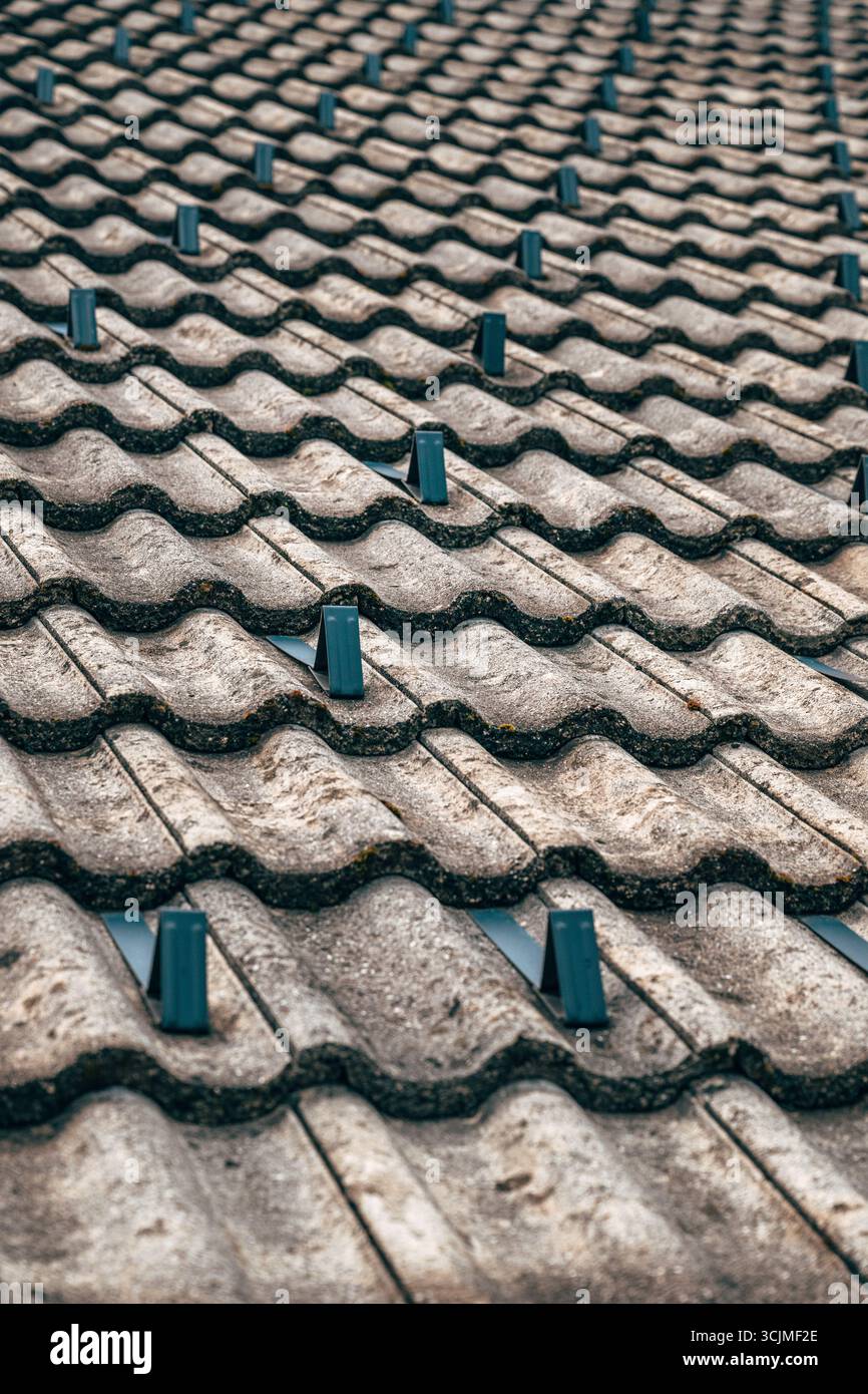 Primo piano di un tetto piastrellato con paraspruzzi in metallo, che mostrano un motivo ripetuto e una superficie ruvida. Messa a fuoco selettiva. Foto Stock