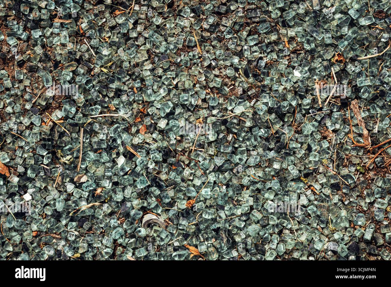 Primo piano di particelle di vetro frantumato riciclano, mostrando frammenti taglienti e superfici riflettenti colorate per il riciclo e la sostenibilità Foto Stock