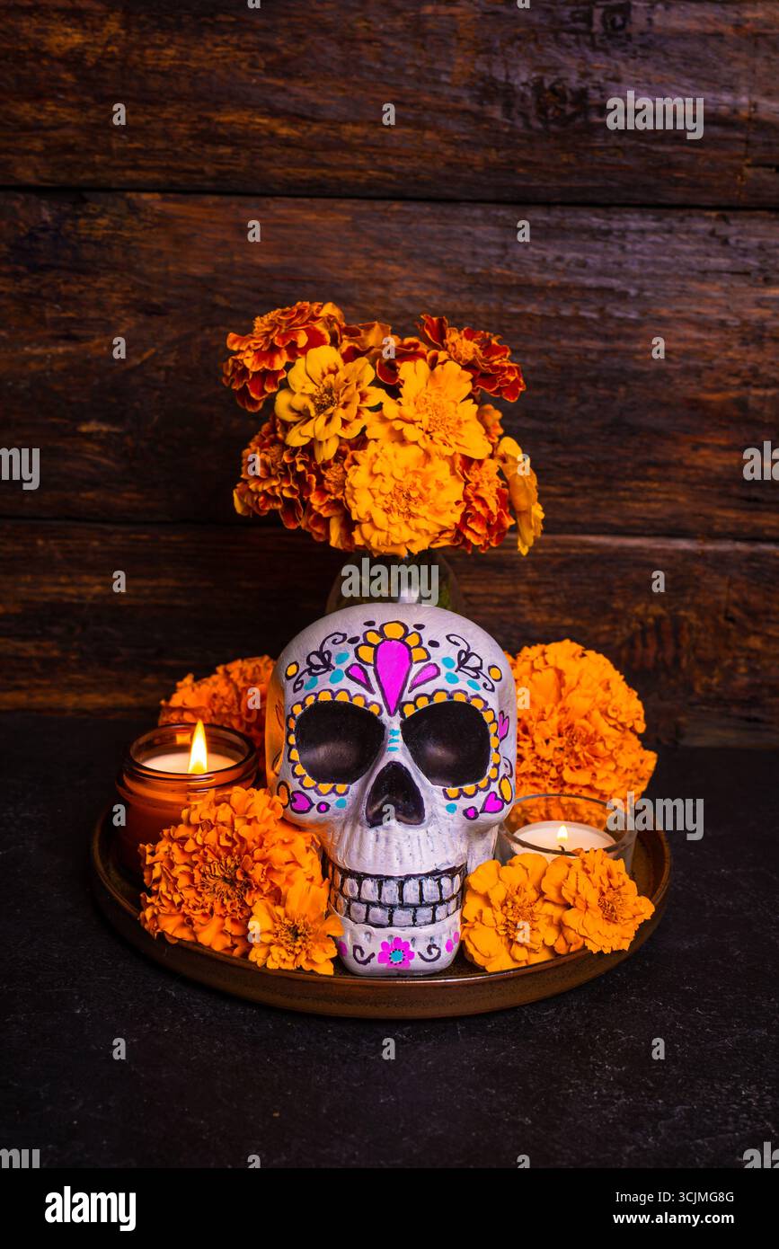 Teschio dipinto con fiori cempasuchil o calendula e candele, altare per la vacanza messicana dia De Los Muertos su sfondo di legno scuro. Giorno del Dea Foto Stock