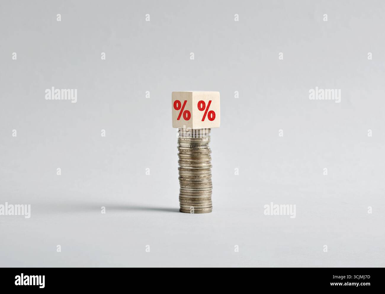 Simbolo di percentuale sul bilanciamento del cubo di legno su una pila di monete che rappresenta un aumento della stabilità finanziaria e del tasso di interesse Foto Stock