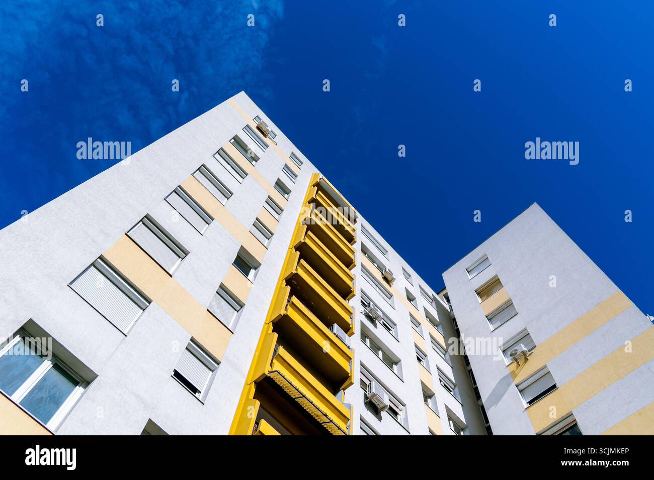 Moderno complesso residenziale con diversi edifici di appartamenti, balconi e design urbano sotto un cielo blu luminoso. Foto Stock