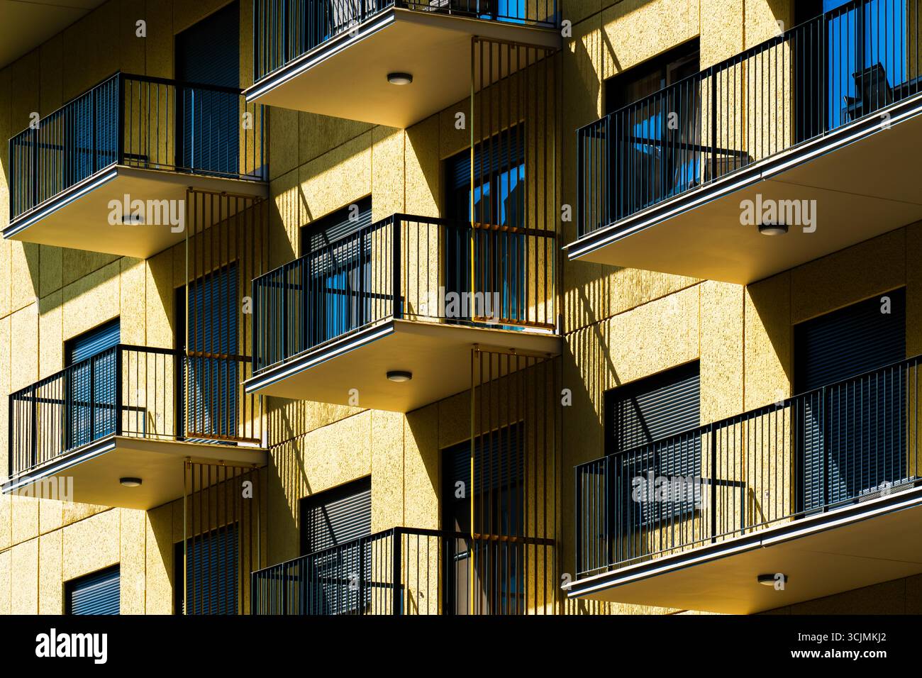 Facciata dell'edificio residenziale con balconi gialli e simmetria delle ringhiere catturata da una spettacolare prospettiva ad angolo basso. Foto Stock