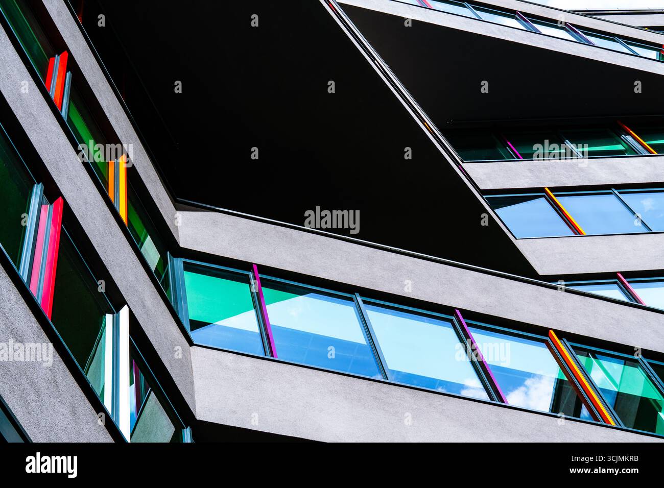 Edificio moderno con pannelli di vetro colorati e linee geometriche nitide che creano una dinamica composizione architettonica urbana. Foto Stock