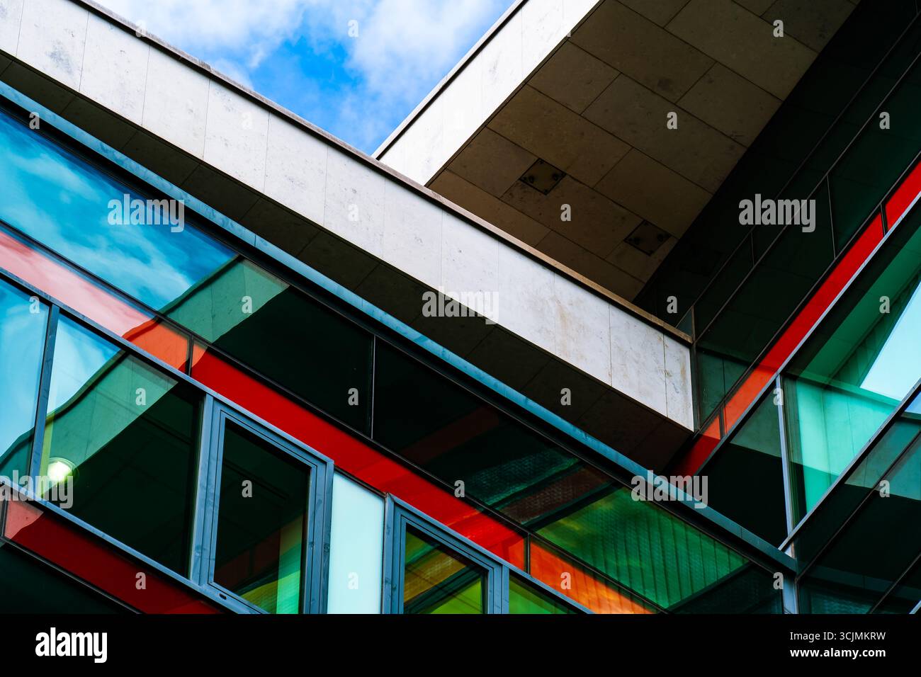Edificio moderno con pannelli di vetro colorati e linee geometriche nitide che creano una dinamica composizione architettonica urbana. Foto Stock